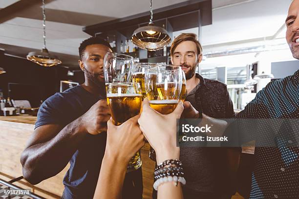 Friends Toasting With Beer In A Pub Stock Photo - Download Image Now - Beer Glass, Celebratory Toast, 2015