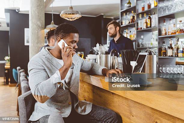 Afro American Man Using Laptop In A Pub Stock Photo - Download Image Now - Laptop, Coffee Shop, Pub