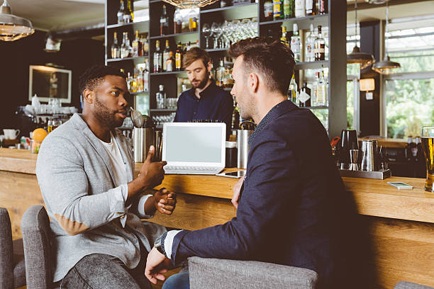 afro-americano homem falando com colega no pub, usando o laptop - coffee shop people discussion three people - fotografias e filmes do acervo