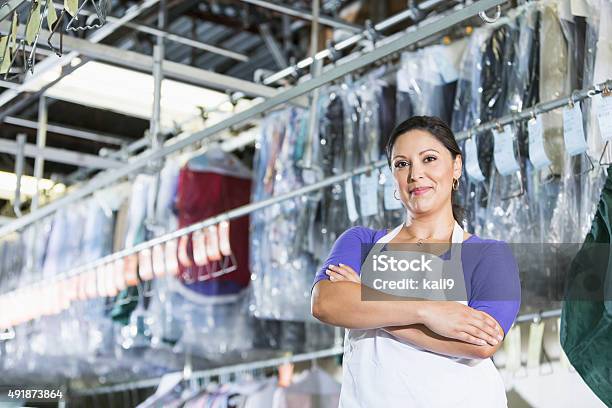 Confident Hispanic Woman In Her Dry Cleaning Store Stock Photo - Download Image Now - Laundromat, Dry Cleaner, Dry Cleaned