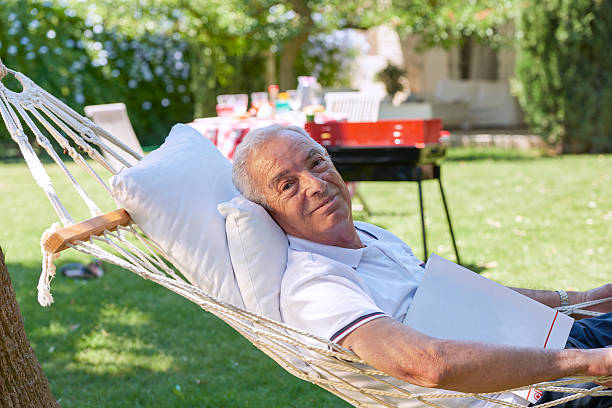 istock Old man relaxing in hammock with a magazine 491888656