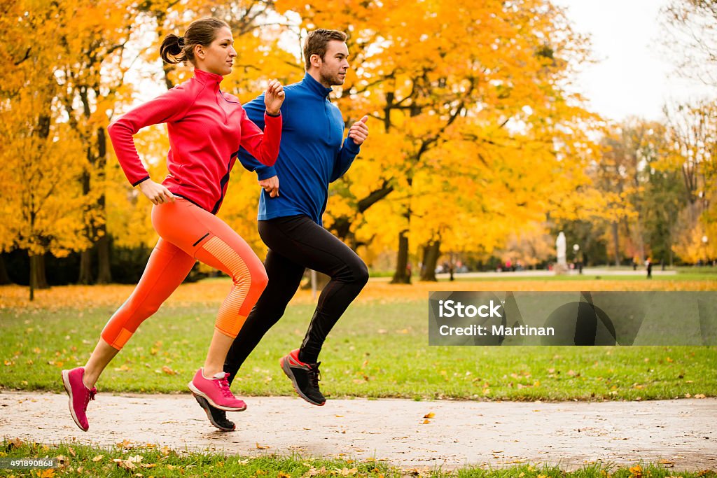 Couple jogging in autumn nature Running together - friends jogging together in park, rear view Running Stock Photo