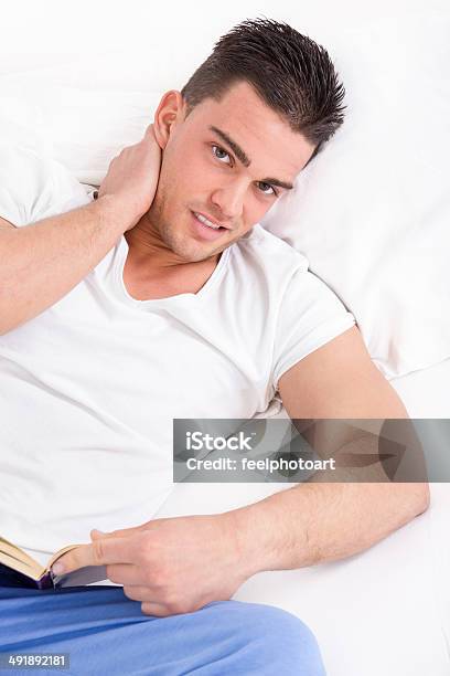 Man With Neck Pain Reading Book In Bed Stock Photo - Download Image Now - Adult, Backache, Beautiful People