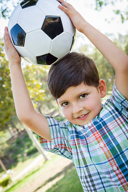 istock Cute Young Boy Playing with Soccer Ball in Park 491892345