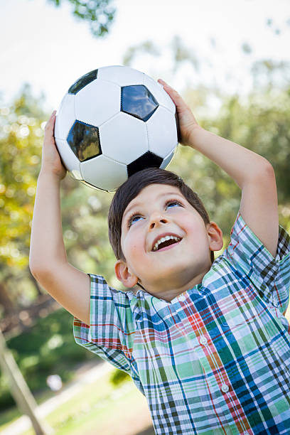 istock Cute Young Boy Playing with Soccer Ball in Park 491892347