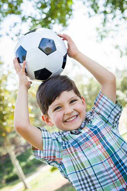 istock Cute Young Boy Playing with Soccer Ball in Park 491892351