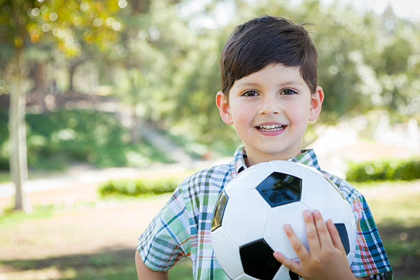 istock Cute Young Boy Playing with Soccer Ball in Park 491892733