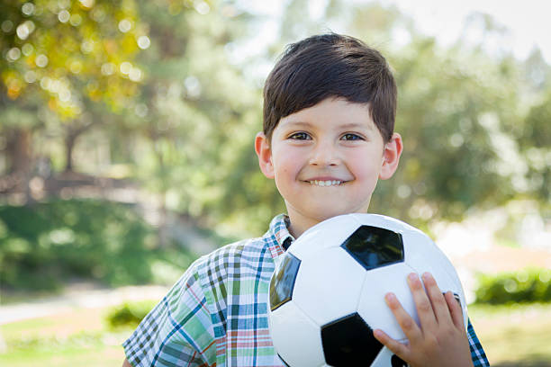 istock Cute Young Boy Playing with Soccer Ball in Park 491892739