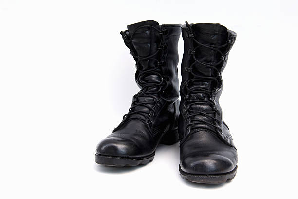 Still life of beautifully aged black leather lace up boots sitting on concrete interior floor