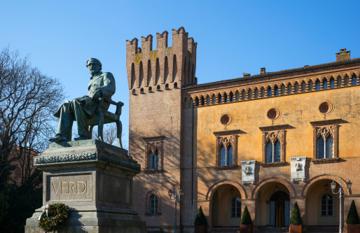 Busseto, Italy - November 29, 2013: The monument of the famous composer Giuseppe Verdi in the country center in front of the Pallavicino Rocca