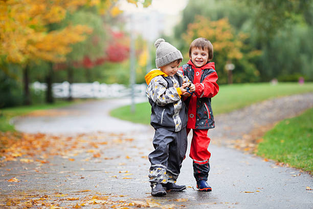 двое детей, борьбе с над игрушка в парк в дождливый день - twin falls стоковые фото и изображения