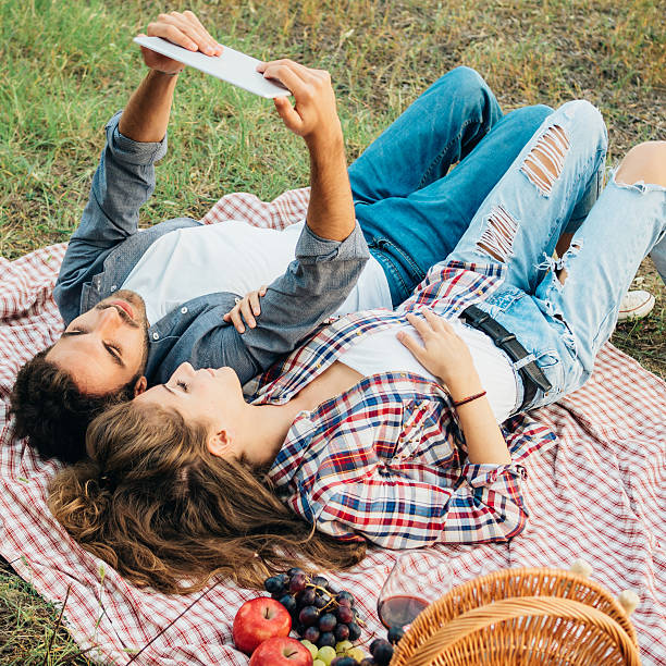 istock Young Couple Using Tablet During Picnic Outdoor 491905436