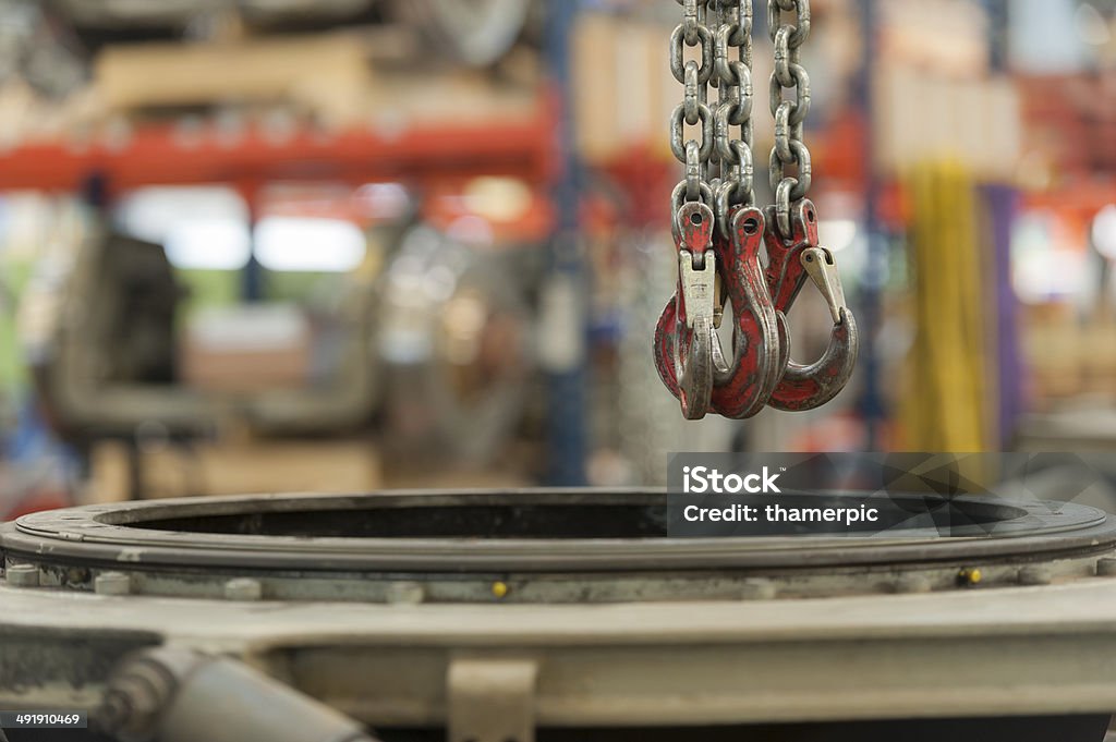 Steel hook and chain is hanging off ceiling Heavy duty hoist at a car factory: Three steel chains with massive hooks are hanging off the ceiling of an industrial facility. Auto Repair Shop Stock Photo