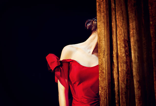 Lady in red Beautiful lady in red dress hiding her face at the stage. stage actress stock pictures, royalty-free photos & images