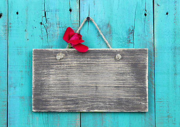 Blank rustic wood sign with red flower hanging on antique wooden background