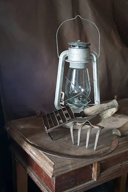 Old-time instruments and kerosine lamp to rest upon wooden table on dark background