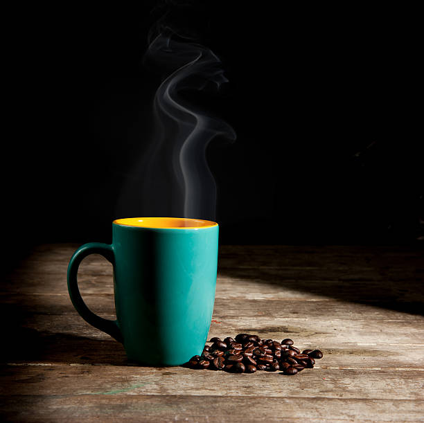Black cup of coffee on the table with scattered beans. Copy space.