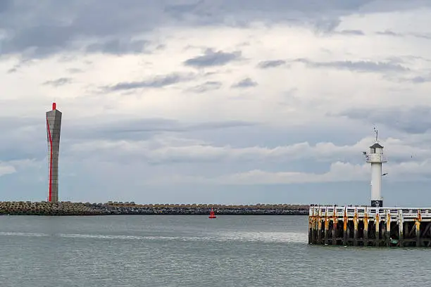 Old-fashioned sea lighthouse and modern radar tower on the longitudinal embankment along the North Sea coast at Ostend, Belgium