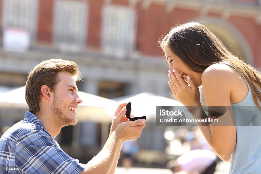 Proposal in the street man asking marry to his girlfriend Proposal in the street with a man asking marry to his happy girlfriend Engagement Stock Photo
