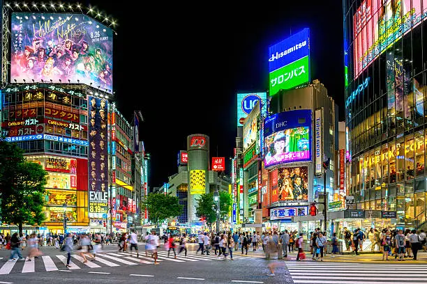 People crossing the famous Shibuya crossing in Tokyo at night.