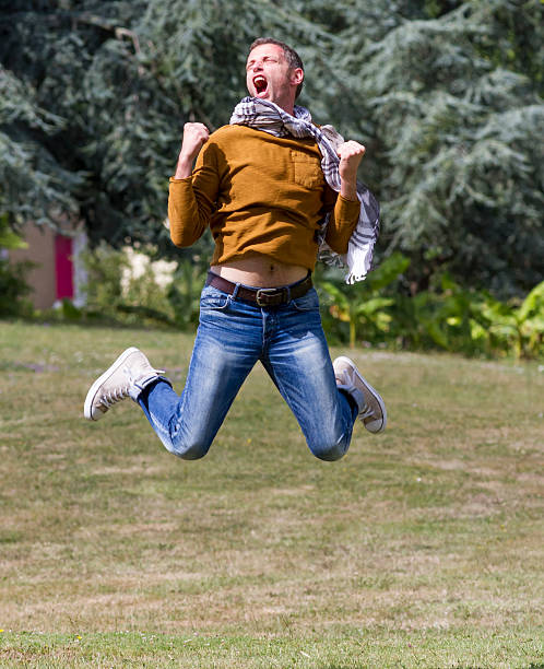 istock ecstatic young man jumping high for success in sunny park 491925902
