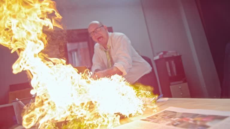 SLO MO Man slamming the burning laptop with hammer