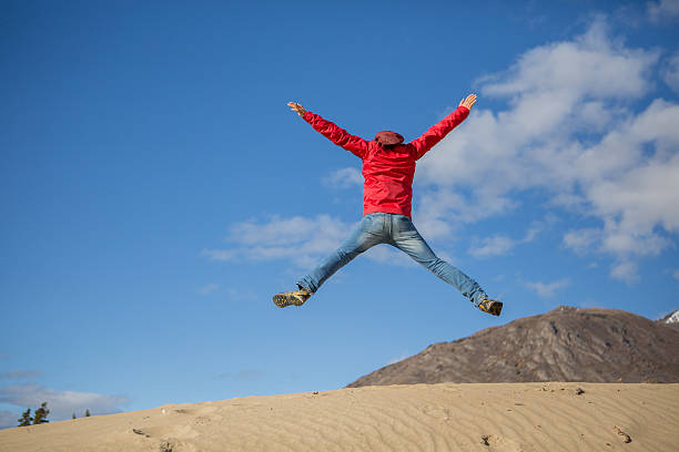 Young cheerful man in desert jumping high up in the air. 