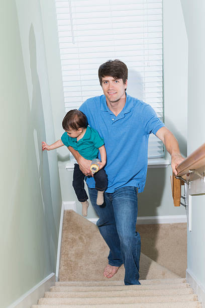 istock Father carrying baby boy up staircase 491936742