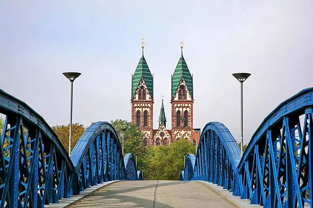 The Stuhlinger bridge leading to Herz-Jesu Cathedral, the gothic cathedral with a high tower in Freiburg, located in southern part of Black Forest of Germany. 