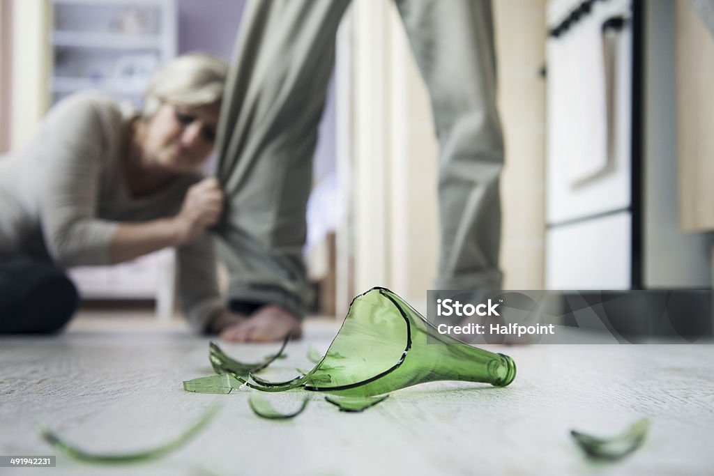 Domestic violence Woman victim of domestic violence and abuse. Mature woman scared of a man with broken bottle 50-59 Years Stock Photo