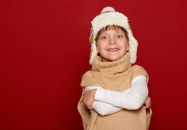 istock girl in hat and sweater posing on red background 491952950