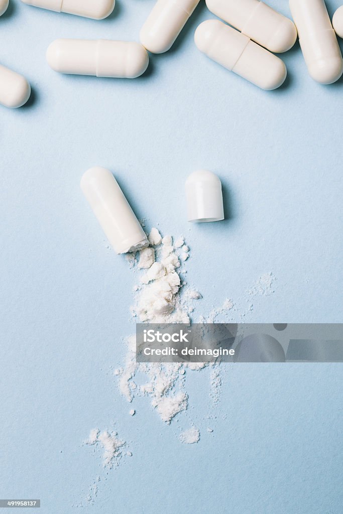 Open capsule Open white capsule on blue background. Capsule - Medicine Stock Photo