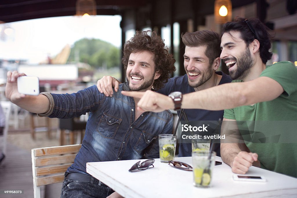 Friends having fun at the bar. Male friends having fun at the bar outdoors, drinking mojito and taking selfies. 20-24 Years Stock Photo