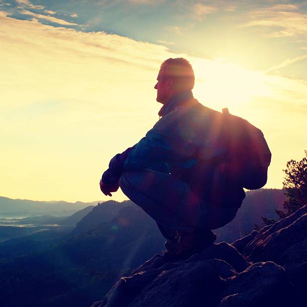 istock Hiker with sporty backpack sit on rocky cliff edge 491959326