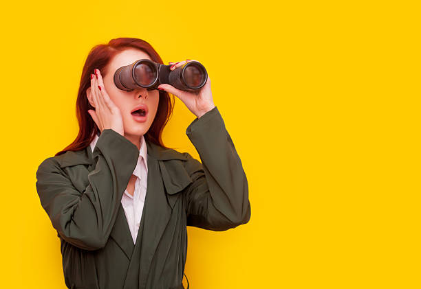 istock woman with binocular on yellow background 491961314