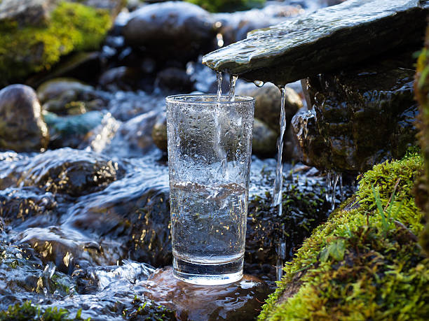 acqua minerale viene versato in vetro - flowing water river spring water foto e immagini stock