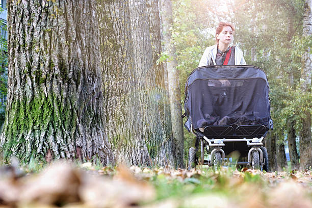 istock Mom with stroller walks in autumn park alley 491974904