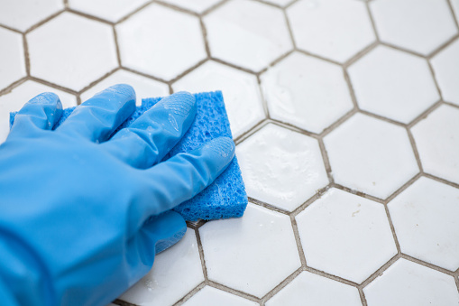 Guantes de limpieza azul sosteniendo una esponja de limpieza de un piso de mosaico photo