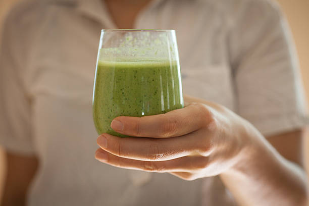 istock woman holding a green smoothie 491978844