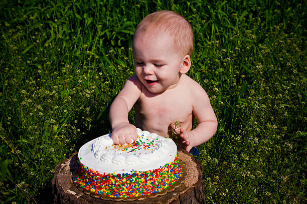 istock Baby Eating Birthday Cake on Tree Stump 491990269