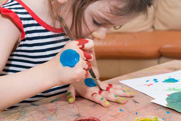 istock Small girl uses paint to draw on her hands 491990735