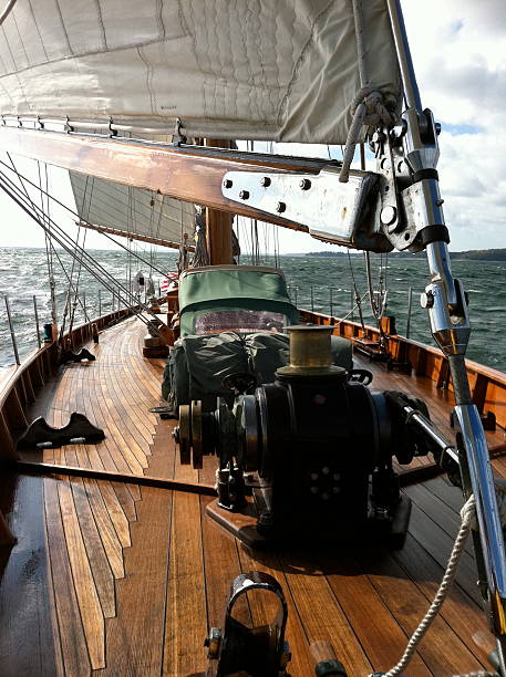 Classic Sailing Yacht Taken from the bow of a classic sailing yacht while underway.  Teak decks and varnished spars oppose angles in this semi-wide angle shot. gaff rigged stock pictures, royalty-free photos & images