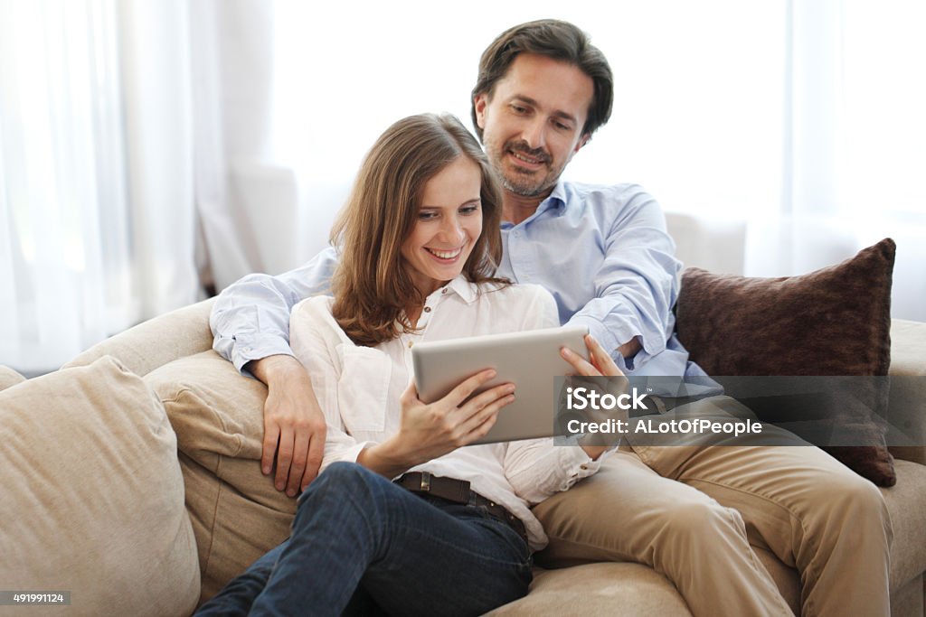 Cheerful couple using tablet Cheerful couple using digital tablet at home 2015 Stock Photo