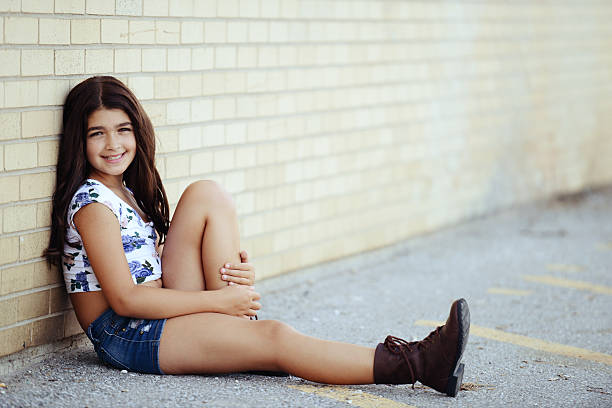 young girl leaning on brick wall in school yard