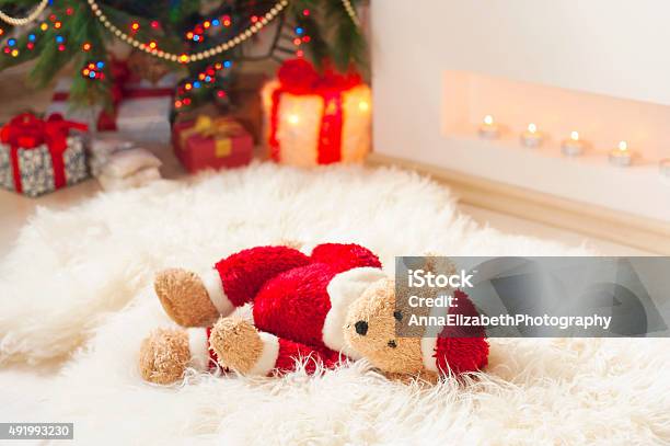 Santa Tedyy Bear Toy On Sheepskin Near Illuminated Christmas Tree Stock Photo - Download Image Now