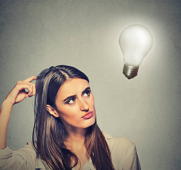 istock woman thinking looking up at bright light bulb 492001224