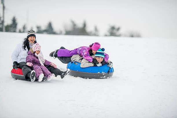 istock Family Happily Riding Inner Tubes Down a Snowy Hill 492001372