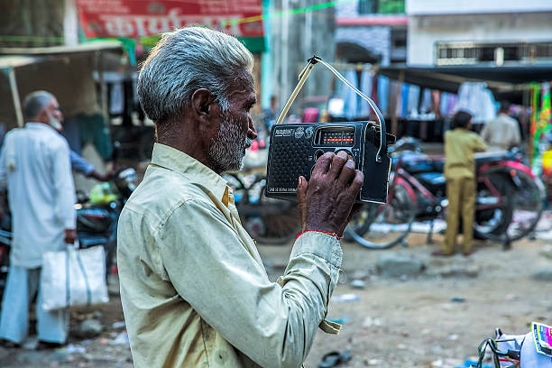 Old man listening to an old fashioned Radio set Baheri, Bareilly, Uttar Pradesh, India, - September 24, 2015: Local market or "Bazar" in Baheri. Old man listening to an old fashioned Radio set. old person listening to radio stock pictures, royalty-free photos & images