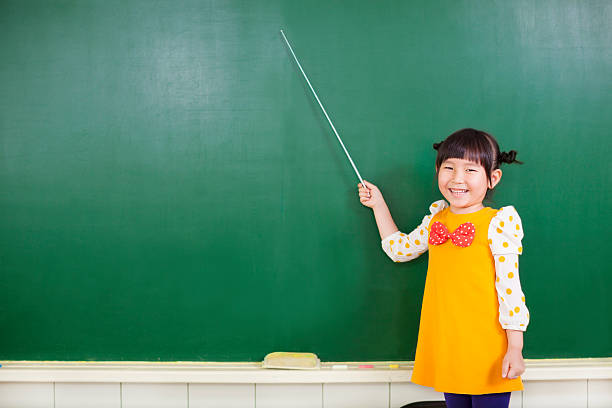asian little girl using a baton to point on a blackboard asian little girl using a baton to point on a blackboard  in a classroom conductors baton photos stock pictures, royalty-free photos & images