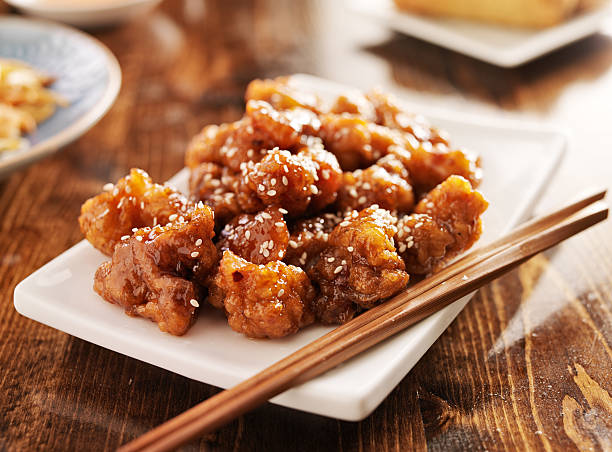 chinese sesame chicken with chopsticks chinese sesame chicken with chopsticks , shot with selective focus. sesame stock pictures, royalty-free photos & images